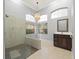 Bright bathroom featuring a glass shower enclosure, stylish vanity, and arched windows at 713 Argyle Pl, Temple Terrace, FL 33617
