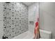 Shower with decorative patterned tile and modern fixtures, alongside a white toilet, creating a clean design at 9027 Merrimoor Blvd, Seminole, FL 33777