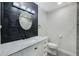 Modern bathroom with sink, toilet, black accents, and decorative mirror and wall at 9027 Merrimoor Blvd, Seminole, FL 33777