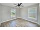 Bright bedroom with gray walls, modern ceiling fan, and two large windows providing natural light and views at 9027 Merrimoor Blvd, Seminole, FL 33777