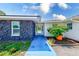 Home featuring a stone facade and blue pathway leading to the glass-paned front door, with landscaping at 9027 Merrimoor Blvd, Seminole, FL 33777