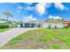 Well-maintained single-story house showcasing stone accents, green lawn, and a long driveway leading to the attached garage at 9027 Merrimoor Blvd, Seminole, FL 33777