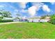Green lawn surrounds house, with rock and white siding, long driveway, and hints of other houses, showing neighborhood at 9027 Merrimoor Blvd, Seminole, FL 33777
