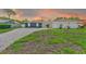 Lovely single-story home in the evening light, featuring stone accents, a spacious driveway, and a well-kept lawn at 9027 Merrimoor Blvd, Seminole, FL 33777