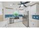 Bright kitchen featuring stainless steel appliances, white cabinets, blue backsplash, and modern fixtures at 9027 Merrimoor Blvd, Seminole, FL 33777