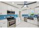 Updated kitchen boasts stainless steel appliances, sleek countertops, white cabinetry, and blue backsplash at 9027 Merrimoor Blvd, Seminole, FL 33777