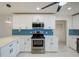 Well-lit kitchen features stainless steel appliances, white cabinets, and a stylish blue backsplash at 9027 Merrimoor Blvd, Seminole, FL 33777
