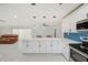 Spacious, open concept kitchen area featuring white cabinets, blue backsplash, and an adjacent living space at 9027 Merrimoor Blvd, Seminole, FL 33777