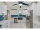 Updated kitchen featuring stainless steel appliances, modern fixtures, and stylish blue backsplash at 9027 Merrimoor Blvd, Seminole, FL 33777