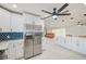 Open kitchen with stainless steel refrigerator, blue backsplash, white cabinets and countertops, plus living area at 9027 Merrimoor Blvd, Seminole, FL 33777
