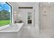 Bright bathroom featuring a glass enclosed shower, freestanding tub, double vanities, and marble floors at 937 Old Welcome Rd, Lithia, FL 33547