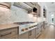 Gas range and stainless hood in updated kitchen with custom cabinets and herringbone tile backsplash at 937 Old Welcome Rd, Lithia, FL 33547