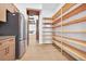 Walk-in pantry with custom wood shelving, adjacent to kitchen with stainless steel refrigerator at 937 Old Welcome Rd, Lithia, FL 33547