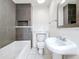 Modern bathroom featuring sleek gray tile, a soaking tub, and a pedestal sink at 1011 Newton S Ave, St Petersburg, FL 33705