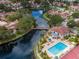 Aerial view of community with mature trees, a lake, a bridge, and community pool with tennis courts at 10330 Carrollwood Ln # 95, Tampa, FL 33618