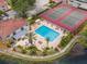 Aerial view of a community pool, tennis courts and surrounding landscaping by a lake at 10330 Carrollwood Ln # 95, Tampa, FL 33618