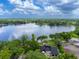 Aerial view showcasing a lakeside home with mature trees surrounding a tranquil body of water at 10502 Lake Williams Dr, Odessa, FL 33556