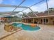 Backyard swimming pool with rock waterfall feature and lounging area inside a screened in lanai with travertine tile at 10502 Lake Williams Dr, Odessa, FL 33556