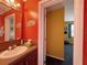 Cozy bathroom with colorful walls, decorative mirror, and dark wood vanity, adjoining another room at 108 W Saint Annes Cir, Apollo Beach, FL 33572