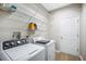 Functional laundry room with washer, dryer, storage shelves, and a white door at 11132 Creek Haven Dr, Riverview, FL 33569