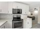 Bright kitchen features white cabinets, subway tile backsplash, stainless steel appliances, and a view to the living room at 11829 104Th St, Largo, FL 33773