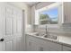 Updated kitchen with white cabinets, gray countertops, stainless steel sink, and a view of the backyard at 11829 104Th St, Largo, FL 33773