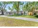Charming single-story home featuring a well-manicured lawn, a gray garage door and beautiful landscaping at 1313 W Carissa Ct, Tampa, FL 33604