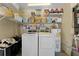 Well-lit laundry room with organized shelving, washer, dryer, and water heater at 1313 W Carissa Ct, Tampa, FL 33604