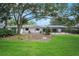 Spacious backyard with mature trees, a patio, and a view of the home's exterior at 13310 Golf Crest Cir, Tampa, FL 33618