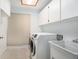 Functional laundry room featuring a washer, dryer, sink, and storage cabinets at 13310 Golf Crest Cir, Tampa, FL 33618