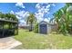Spacious backyard featuring lush green grass, a storage shed, a shaded structure and privacy fence at 14105 Farmington Blvd, Tampa, FL 33625