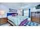 Comfortable bedroom features a large bed with tropical bedding, wood-look floors, and a bright painting at 14105 Farmington Blvd, Tampa, FL 33625