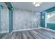 Minimalist bedroom featuring wood-look floors, a large window, and a mirrored closet door for added space at 14105 Farmington Blvd, Tampa, FL 33625