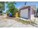 Garage exterior with a white door and lilac-colored walls surrounded by greenery at 1822 1St Se St, St Petersburg, FL 33705