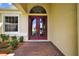Red double front doors, brick pathway, and sidelight window offer curb appeal at 1835 Fircrest Ct, Wesley Chapel, FL 33543