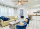 Bright living room with a ceiling fan, couch, chairs, table and an open kitchen with white cabinets at 1887 Springtime Ave, Clearwater, FL 33755