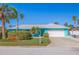 Charming turquoise waterfront home featuring lush landscaping, palm trees, and an attached two-car garage at 2010 E Vina Del Mar Blvd, St Pete Beach, FL 33706