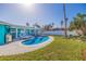 Backyard featuring a sparkling pool, covered patio, manicured lawn, and tropical landscaping at 2010 E Vina Del Mar Blvd, St Pete Beach, FL 33706
