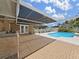 Covered patio and brick flooring with a view of the pool, fence, and lush landscaping at 2209 Kingswood Ln, Brandon, FL 33511
