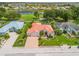 Expansive aerial view featuring a beautiful home with a tile roof, manicured lawn, and paver driveway in a lakeside community at 2221 Platinum Dr, Sun City Center, FL 33573