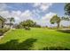 Beautiful backyard with mature trees, lush green grass, and view to golf course at 2221 Platinum Dr, Sun City Center, FL 33573