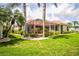 Expansive backyard with a screened-in patio, lush landscaping, and a well-maintained lawn at 2221 Platinum Dr, Sun City Center, FL 33573