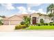 Charming home showcasing a paver driveway, lush landscaping, and a three-car garage, creating an inviting curb appeal at 2221 Platinum Dr, Sun City Center, FL 33573