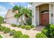 Elegant home entrance with a brick walkway, lush landscaping, and a welcoming front door, creating an inviting curb appeal at 2221 Platinum Dr, Sun City Center, FL 33573