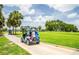 Golf cart parked on a paved path showcasing golf course access and the beautiful landscaping in the community at 2221 Platinum Dr, Sun City Center, FL 33573