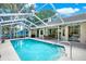 View of screened-in pool with palm trees and the home in the background at 2454 Shadecrest Rd, Land O Lakes, FL 34639