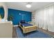 Bright bedroom with blue accent wall, unique car bed, hardwood floors, and white sheer curtains at 2819 Safe Harbor Dr, Tampa, FL 33618