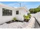 Side view of a clean white home, featuring a walkway with white rock and well-maintained lawn at 3381 19Th Sw Pl, Largo, FL 33774
