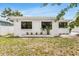 Side view of a clean white home, featuring garden bed with black frame windows and well-maintained lawn at 3381 19Th Sw Pl, Largo, FL 33774