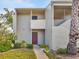 Inviting condo exterior featuring a private balcony, well-manicured landscaping, and a red front door at 401 Windrush Bay Dr, Tarpon Springs, FL 34689